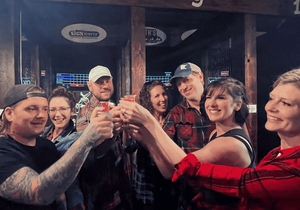 A group of axe throwing friends celebrating a good time throwing axes and taking a drinking break in between throws